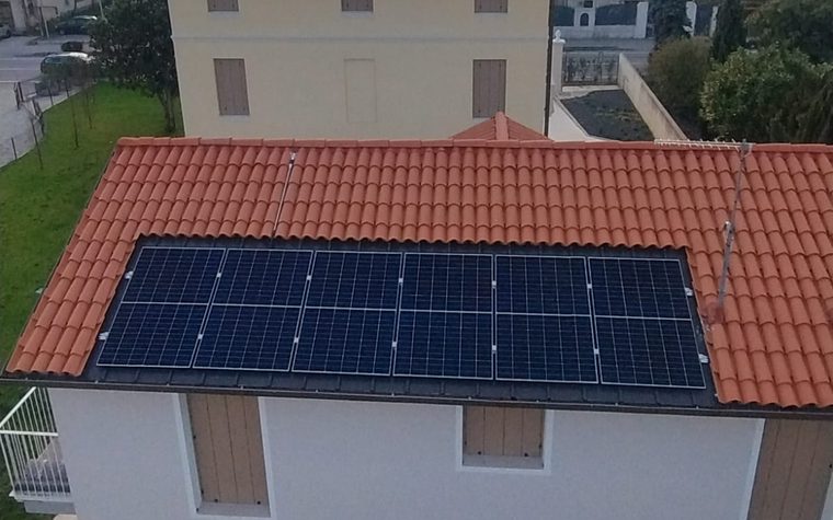 Moduli fotovoltaici installati sulla falda di un tetto in coppi, al tramonto